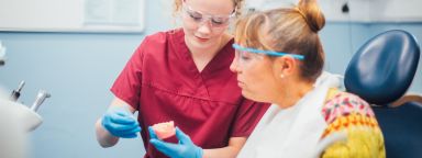 An undergraduate student shows a patient some teeth.