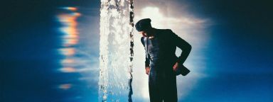 A photograph of composer Erland Cooper next to a vertical ice sculpture, taken by photographer Alex Kozobolis