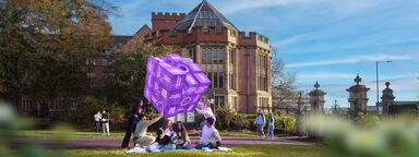 Students sitting in Weston Park looking up at a purple fortune telling cube that represents the different experiences people have at the University of Sheffield