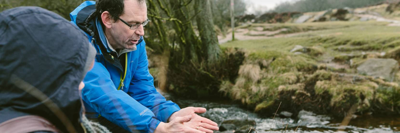 A technician instructs a student by a river