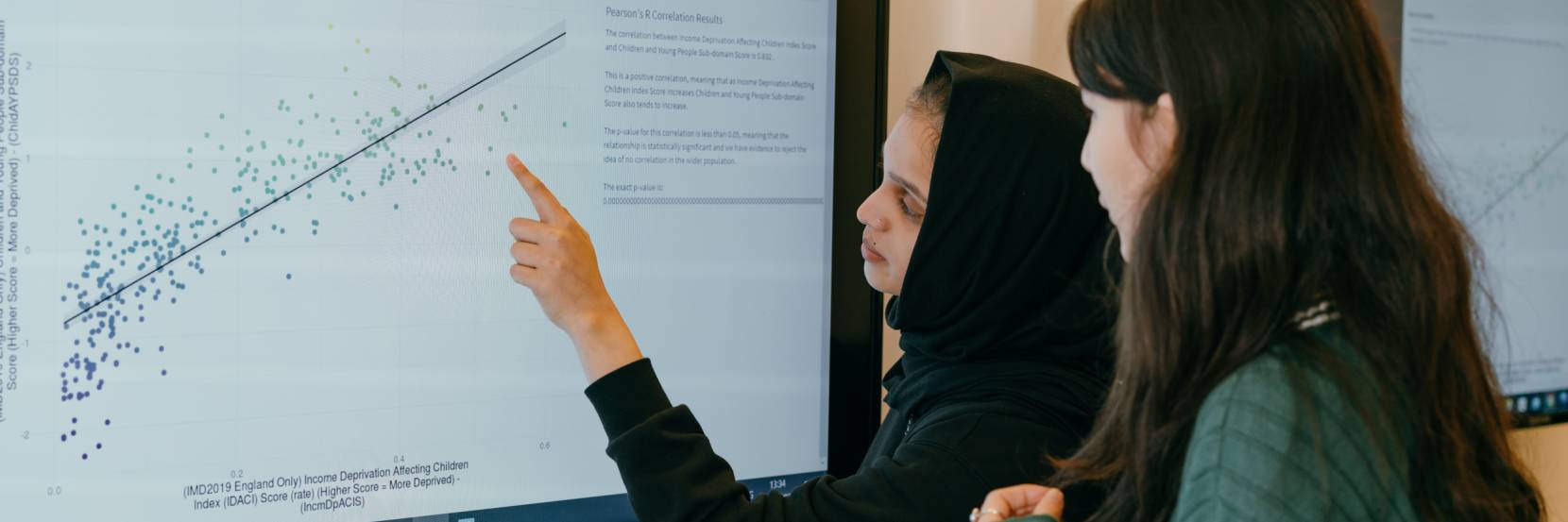 Two students look a graph on a large screen.