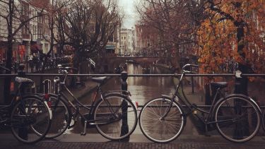 Two bikes near a river in Holland. 