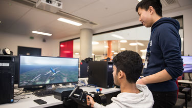 An image of two students using the flight simulator