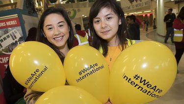 Two students holding # we are international balloons