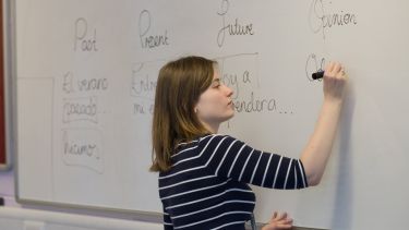A PGDE student writes on a whiteboard