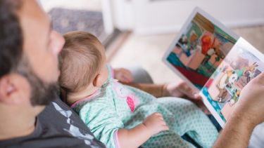 Photograph of father reading to baby