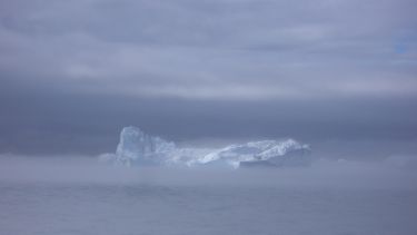 An iceberg far away surrounded by mist
