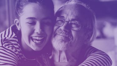 A girl is hugging an older man. They are both smiling. The image has a purple-blue filter 