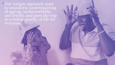 Picture of young girl and older man. Both are smiling, pulling fun faces and wearing home made newspaper hats. There is a purple filter over the image.