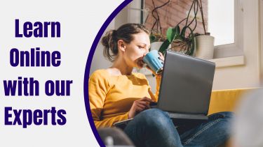 A woman in a yellow jumper drinks from a blue mug while looking at her latop