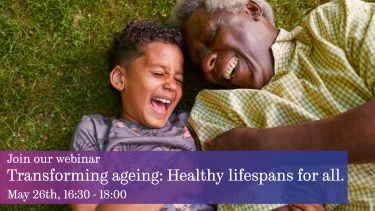 Grandson and grandfather laughing while laying on grass