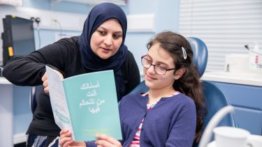 Child reads book with female dentist