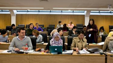 A photograph of a diverse group of MBA students in a lecture theatre.