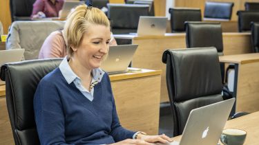 Joanne Moxon wearing a blue jumper sat in a lecture theatre.