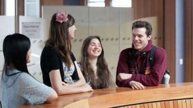 Four modern languages students inside a University building talking to each other