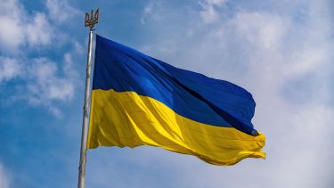 The flag of Ukraine flying with a blue sky in the background