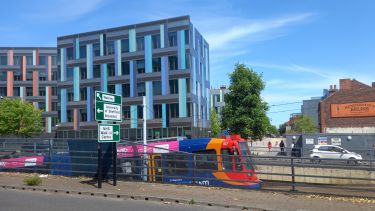 Supertram emerging from tunnel at University Tram Stop, Jessop West building in background