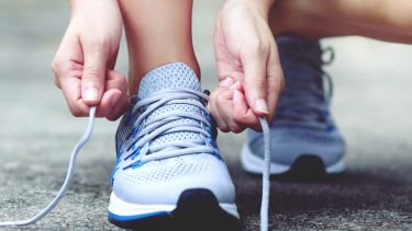 Image of a person crouching to tie their trainer laces