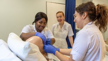 Three nursing students working on a practice dummy