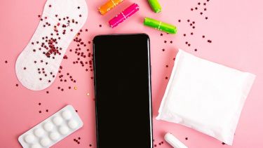 A smartphone, painkiller pills, tampons, and sanitary towels covered in red glitter