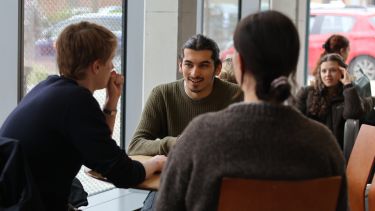 Three students sitting in the cafe chatting together