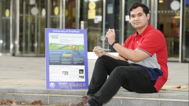 Photograph of Aiman with his poster and trophy after winning the public vote for the 'Champion of Champions' competition at 'Engineering, You're Hired!'