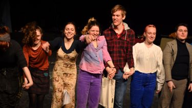 Group of student actors at the end of a play smiling ready to take a bow