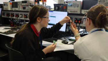 Photograph of students helping each other with one of the tasks at Girls into Electronics day
