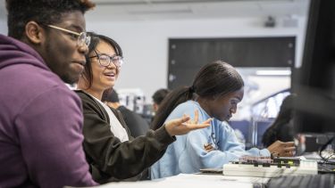 Photograph of students smiling at a computer screen