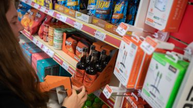A girl unpackaging Hendersons relish onto a shelf in a store