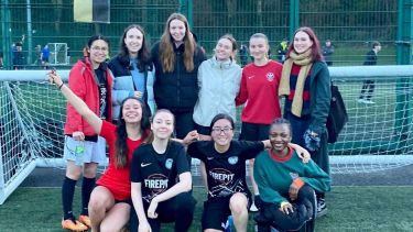 PolSoc women's football team posing happily in front of a goal net