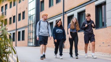 Four students walking towards the camera talking