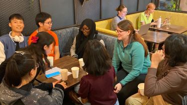 International students sitting around a table at Coffee Revolution enjoying a drink