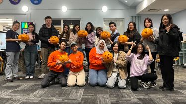 A group of students show the pumpkins that they have carved