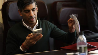Rishi Sunak looking at a phone, whilst on a train 