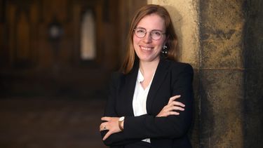 Amy Orben standing by a wall