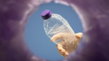 A close up of a plastic bottle being put in a bin