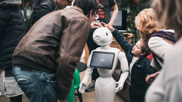 Group of people touching a robot