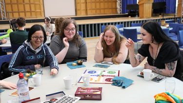 Four students sitting around a table, talking and laughing.
