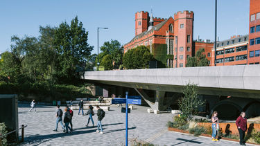 Students walking across the concourse on a sunny outside the student union