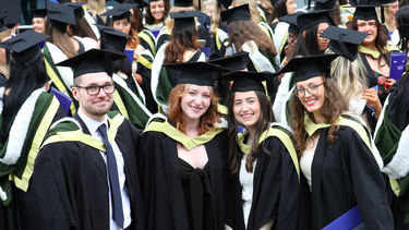 Group of happy graduating students standing outside