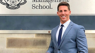 Michael Duffy Jr. stood in front of the Management School sign.