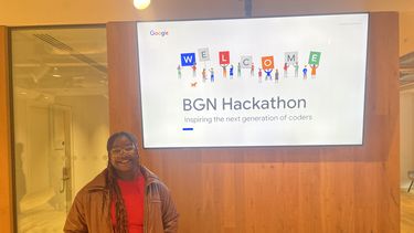 Demi infront of a slide showing 'Welcome to the BGN Hackathon'