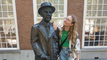 statue of author Louis Couperus with a student looking at him 