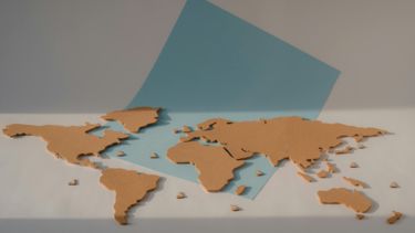 3D World Map in brown with a blue square background. 