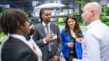 People holding drinks, stood networking in a group