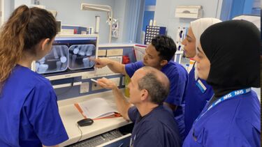 Dental students gathered around a monitor discussing an x-ray of some teeth