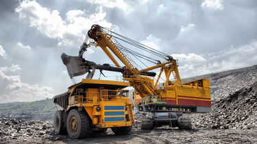 Trucks in a mine setting, one is filling the other with mined material