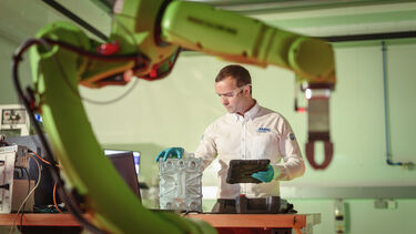 A engineer at the University of «Ӱҵ AMRC stood next to a robotic arm