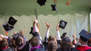 students in graduation gowns celebrating